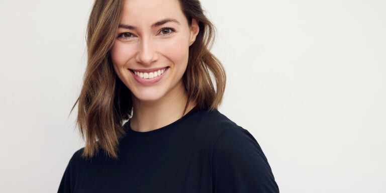 Portrait of beautiful natural brunette woman, smiling and looking in camera with white teeth. Close-up portrait of cute female girl in black t-shirt isolated on white background.