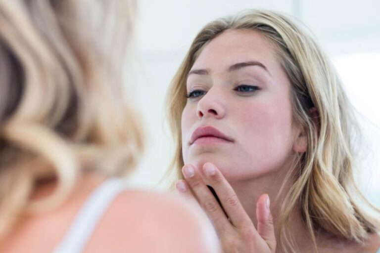 Focused beautiful woman looking at herself in the bathroom