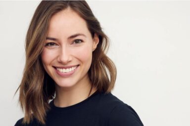 Portrait of beautiful natural brunette woman, smiling and looking in camera with white teeth. Close-up portrait of cute female girl in black t-shirt isolated on white background.